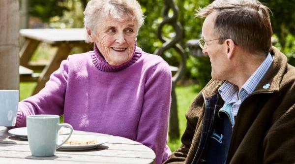 Mark and his mum chatting in the garden with cups of tea