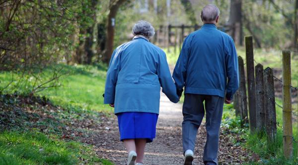A couple walking down a country path and holding hands, they are both wearing blue clothes